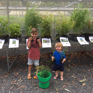 two young boys holding native plants from the community nursery
