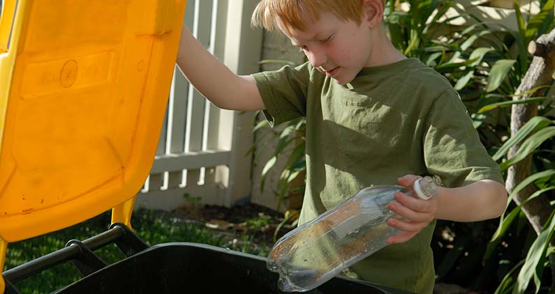 boy putting bottle in recycling bin