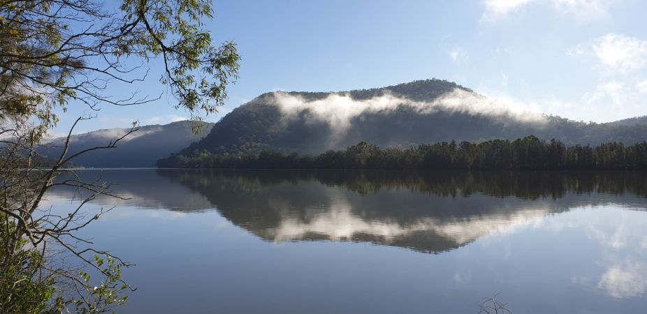 <strong>© Verne Mantova – Hawkesbury River Wisemans Ferry</strong><br>I walk often along my road which is adjacent to the Hawkesbury River where this photo was taken in Wisemans Ferry. I also observe how the river and surrounds change through the seasons. I took this photo as the reflections on the water at the time were particularly beautiful. They also show the renewal of the bush post the November December bushfire 2019.