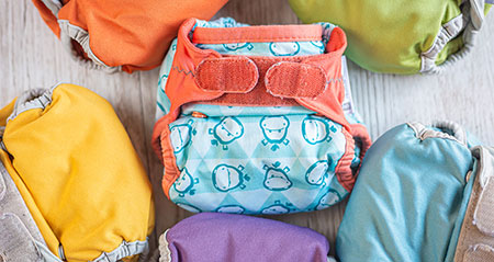 washable nappies with monkeys, top-view on white wooden background