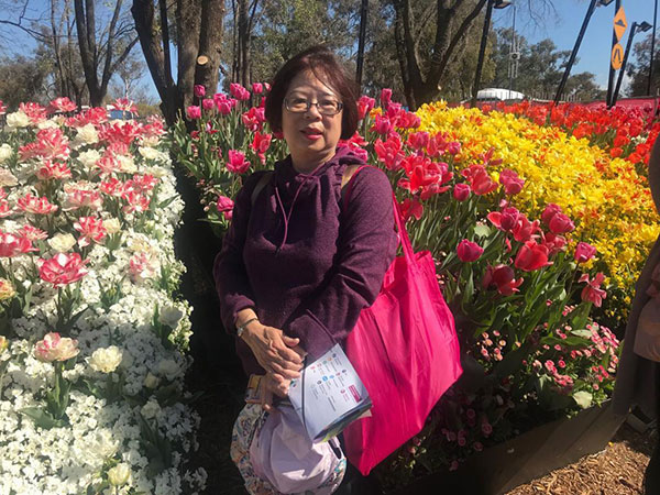 female in front of colourful garden display