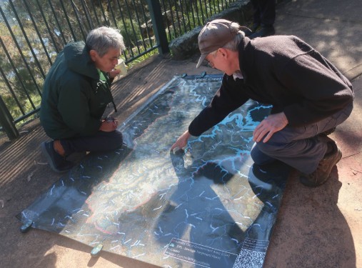 2 males looking at map on ground