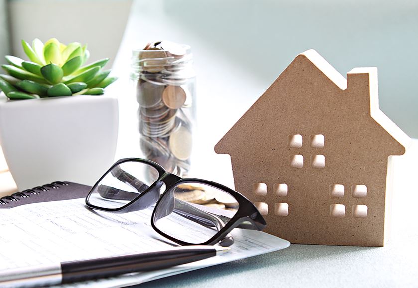 minature house on table with jar and pair of glasses