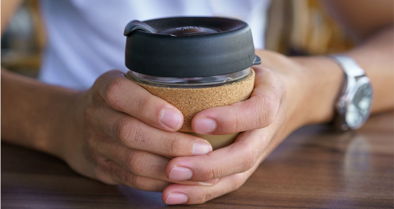 hands holding reusable coffee cup