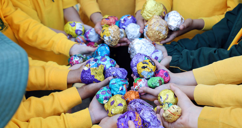 school kids holding empty easter egg wrappers