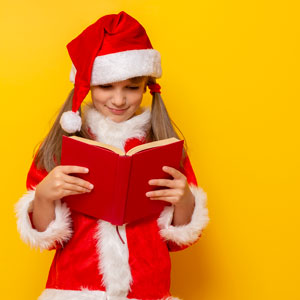 girl reading a book in a Santa suit