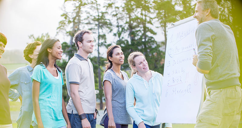 Man leading meeting at flipchart in field