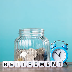 glass jar with coins inside with 'retirement' sign in front