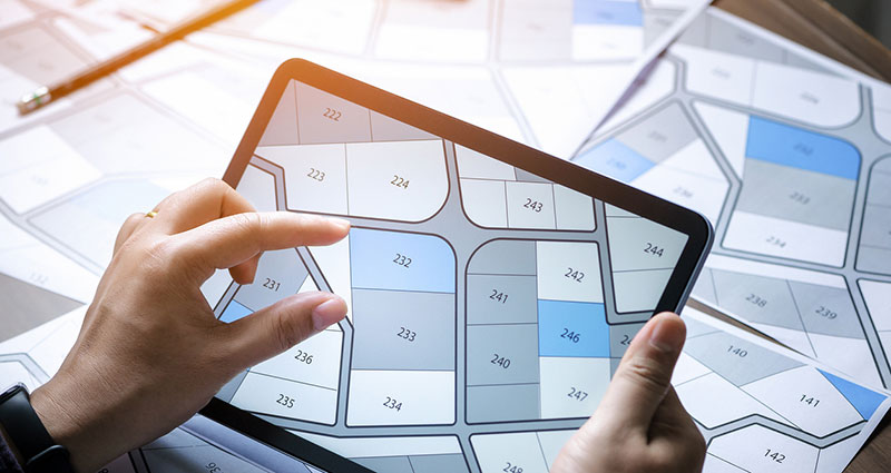 a man searching building plot on a cadastral plan to choose and buy a building plot for house construction on a digital tablet