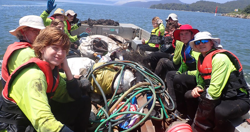 group on boat with collected rubbish