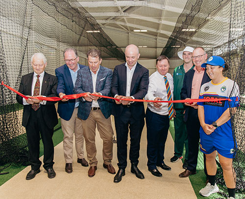 group standing in front of cricket net cutting ribbon