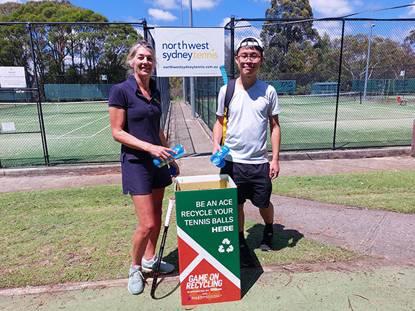 male and female in front of tennis courts with recycling box for tennis balls
