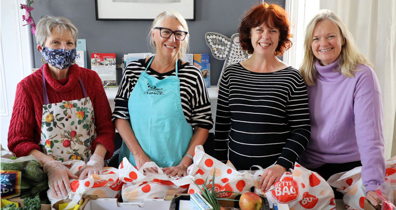 Four ladies standing over groceries