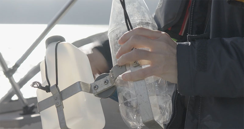 person holding water sampling bottle