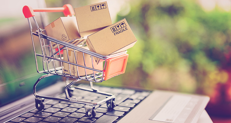 minature shopping trolley with boxes sitting on laptop