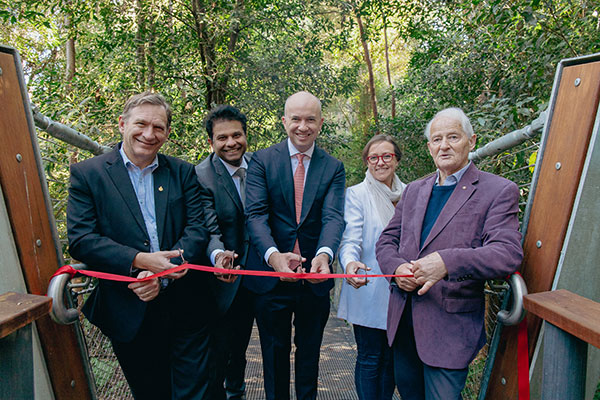 group standing in front of bridge cutting ribbon