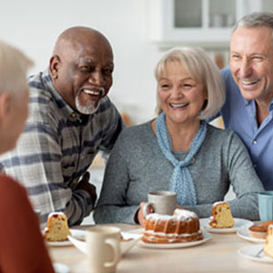 group of older people around a table with cakes
