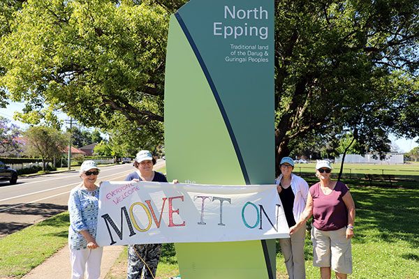 group on roadside holding banner with text 'move it on