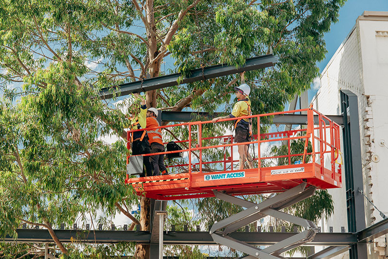 workers on elevated platform directing steel girders into position