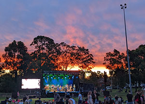 crowd in front of large screen at sunset