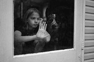 child looking through door window with dog