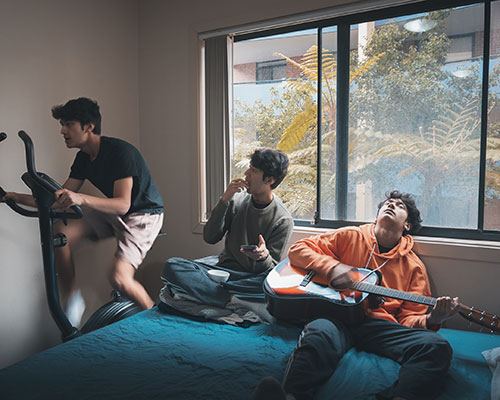 boys in room sitting on bed with guitar