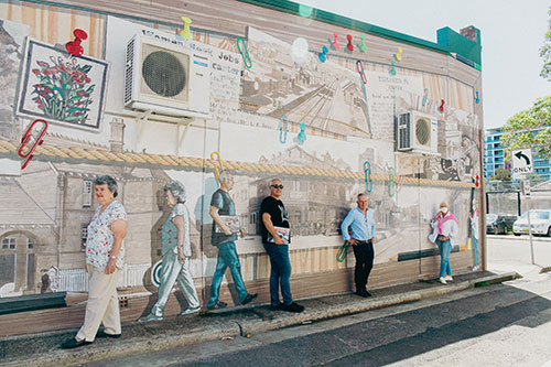 people standing in front of wall mural on street corner