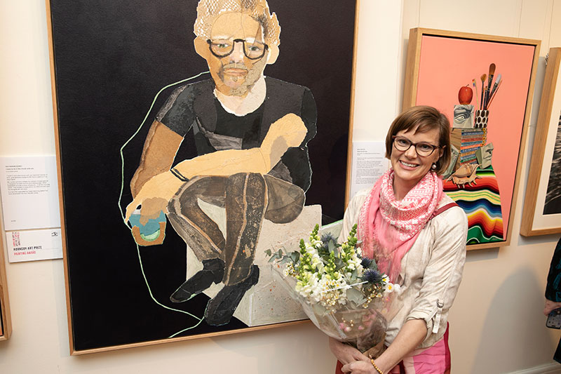 Silke Raetze standing next to winning painting at art galllery